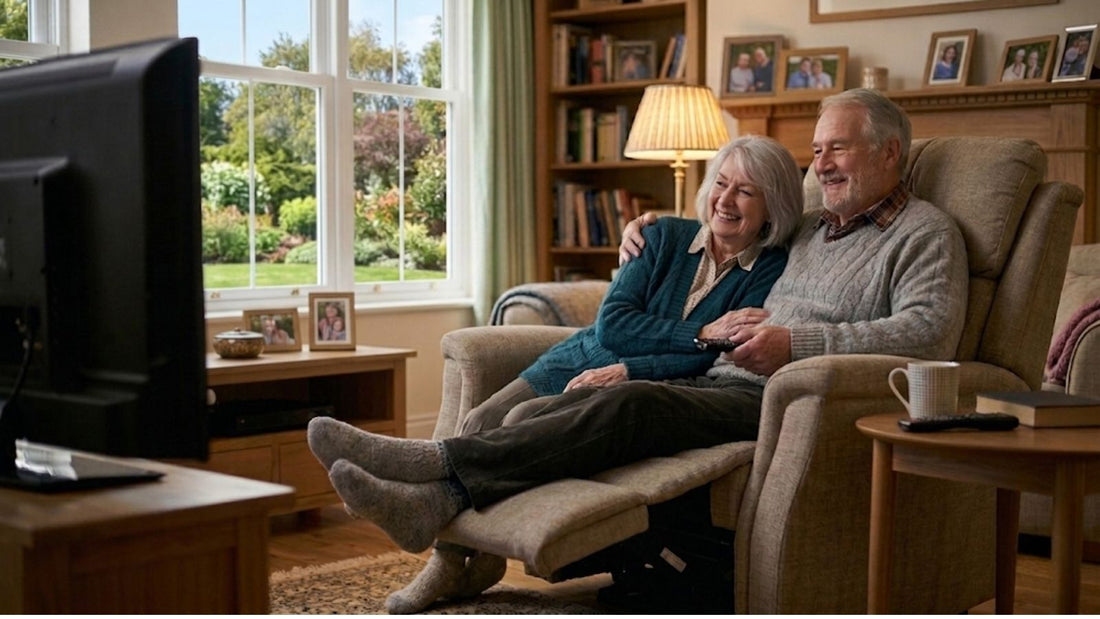 A happy senior couple sitting together in a comfortable recliner chair, watching television in a cozy American living room.
