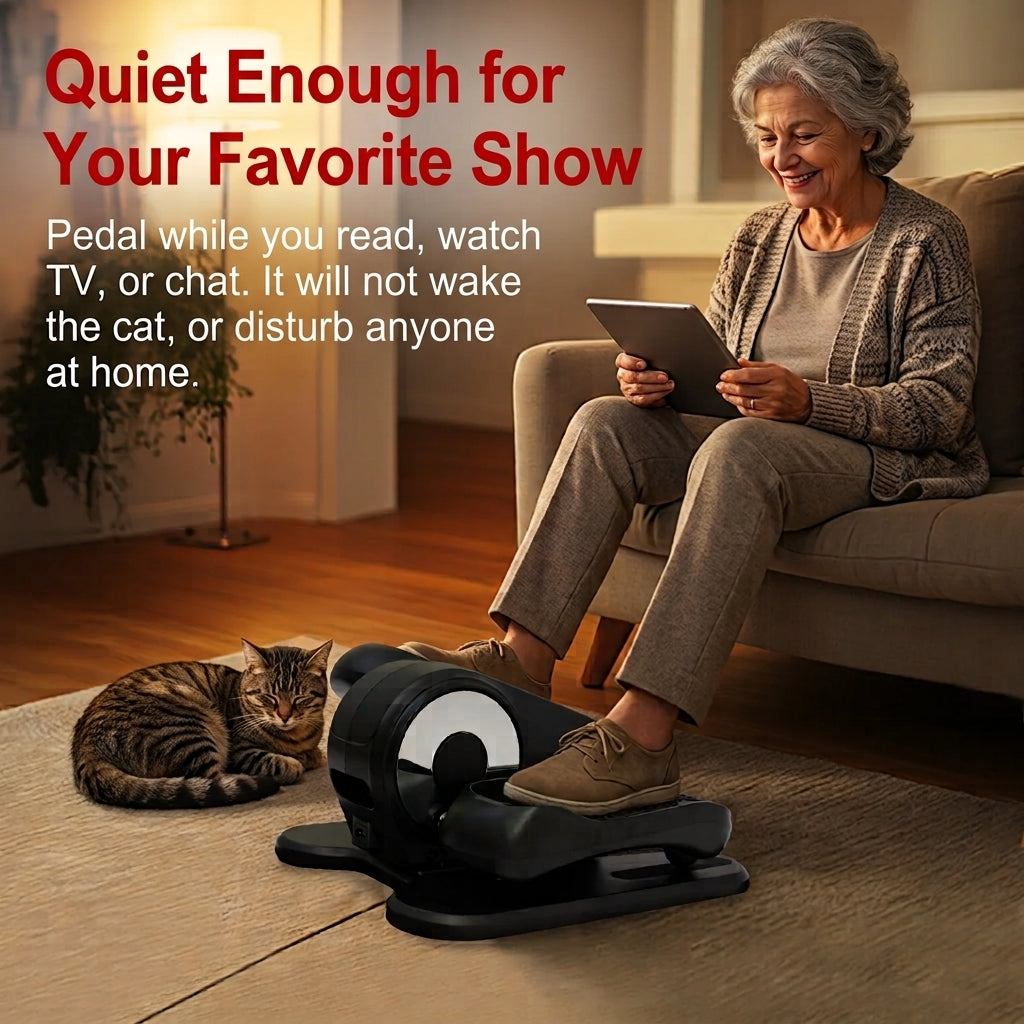 Senior woman relaxing in an armchair using a tablet while quietly pedaling an under desk elliptical machine next to a sleeping cat.